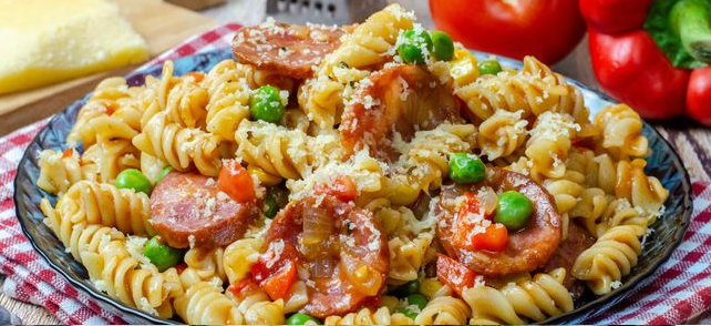 Pasta in tomato sauce with sausage, sweet pepper, peas and corn