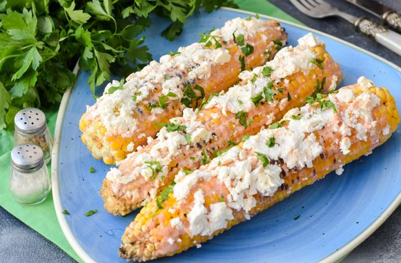 Grilled corn with sour cream and mayonnaise sauce and cheese