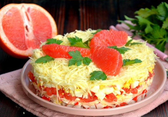 Layered salad with crab sticks, cheese, grapefruit and eggs