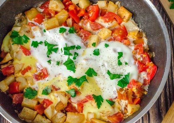 Fried eggs with potatoes, tomatoes and onions
