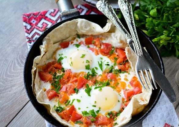Fried eggs on pita bread, with cheese and tomatoes